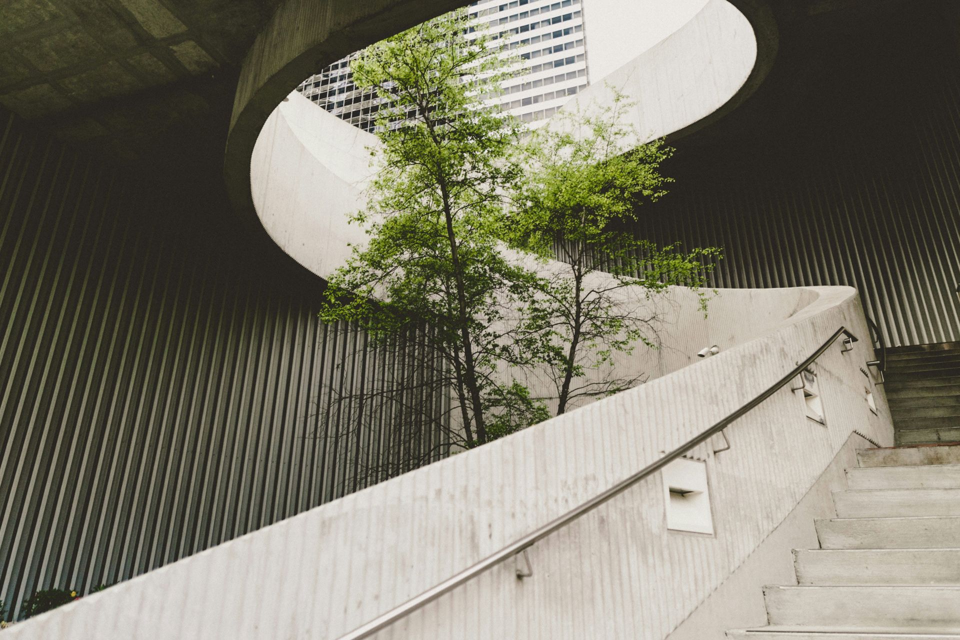 Low angle view from a bottom step, looking up a concrete spiral staircase.